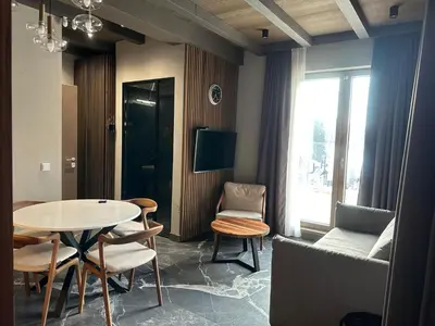 a living room with a table and chairs and a tv at Apartman Stotka in Kopaonik