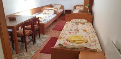 a room with three beds and a table and a dining room at Apartman Sivi Vuk Kopaonik in Kopaonik