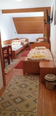a bedroom with two beds and a table and a rug at Apartman Sivi Vuk Kopaonik in Kopaonik