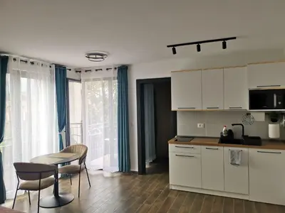 a kitchen with white cabinets and a table and chairs at LILLY apartman in Vrnjačka Banja