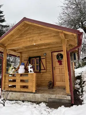 a small wooden cabin with a snowman on the porch at Brvnara Novičić in Vrnjačka Banja