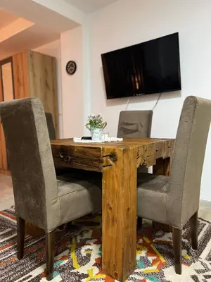 a wooden table with chairs and a television on a wall at Apartman Vučko in Kopaonik