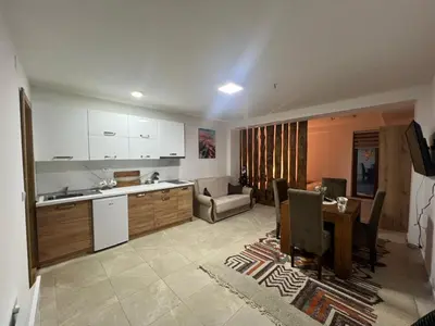 a kitchen and a living room with a table and chairs at Apartman Vučko in Kopaonik