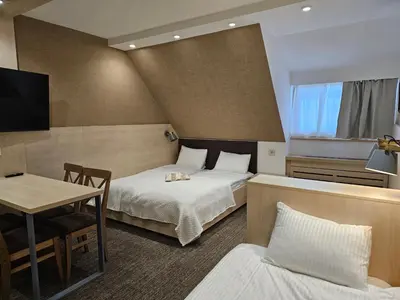 a hotel room with two beds and a table and a desk at Konak Zvečan 307 in Kopaonik