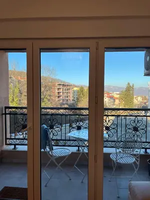 a balcony with sliding glass doors with a table and chairs at Eden Apartman Vrnjačka Banja in Vrnjačka Banja