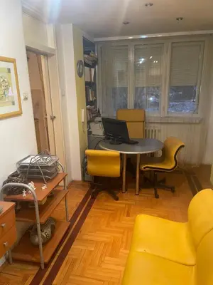 a room with a table and chairs and a laptop at Sindjelicev trg apartment in Niš