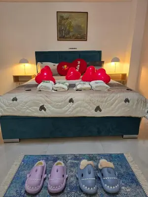 a bed with red pillows and pairs of shoes on it at Doksim Luxury Apartments 201 in Pirot