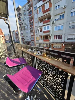 two pink chairs on a balcony with a building at Doksim Luxury Apartments 201 in Pirot