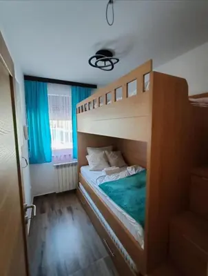 a bedroom with a bunk bed with blue curtains at Apartman MPS Kopaonik-Free Spa in Kopaonik