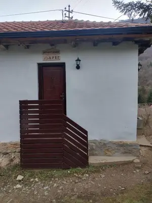 a small white building with a door and a fence at Apartman BREG in Pirot