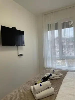 a bedroom with towels on a bed with a flat screen tv at Apartment Luka Lux in Vrnjačka Banja