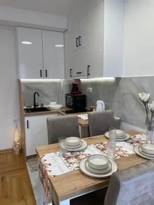 a kitchen with a wooden table with plates on it at Apartment Luka Lux in Vrnjačka Banja
