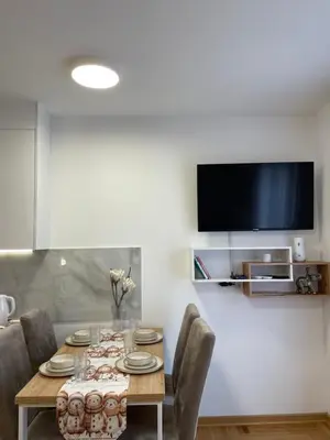 a dining room table with chairs and a tv on a wall at Apartment Luka Lux in Vrnjačka Banja