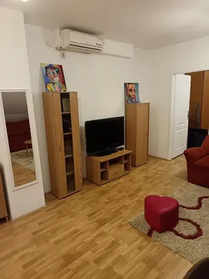 a living room with a television and a red chair at Niš,centar udobnosti in Niš