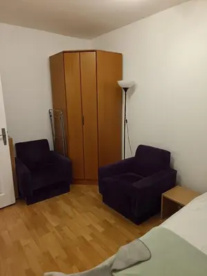 a bedroom with two chairs and a bed and a cabinet at Niš,centar udobnosti in Niš
