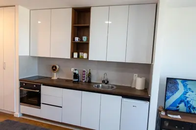 a kitchen with white cabinets and a sink at Planet Residence Royal Studio & SPA in Niš
