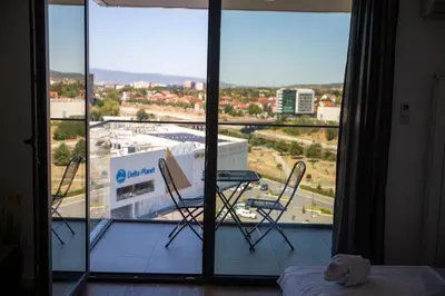 a room with a balcony with chairs and a large window at Planet Residence Royal Studio & SPA in Niš