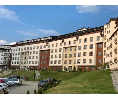 a large building with cars parked in a parking lot at Apartmani Aki in Kopaonik
