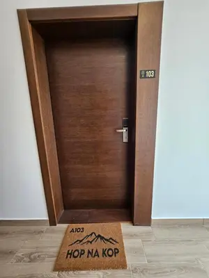 a wooden door with a welcome mat in front of it at Hop na Kop Residence Hill App 103 in Kopaonik
