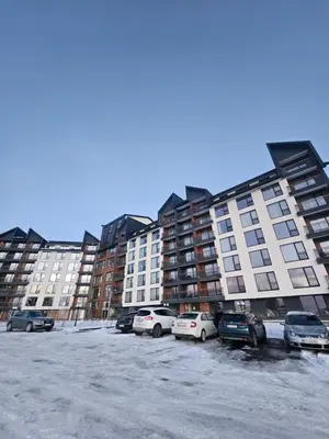 a parking lot with cars parked in front of tall buildings at Hop na Kop Residence Hill App 103 in Kopaonik