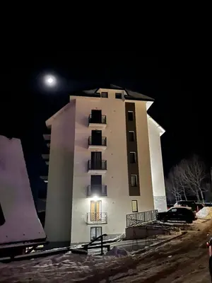a tall building at night with the moon behind it at Cozy Kop, Free Parking, SPA for additional price in Kopaonik