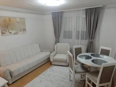 a living room with a white couch and a table at Apartman Milosavljević in Železnička Stanica Ćele Kula