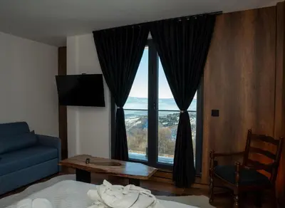 a bedroom with a blue couch and a large window at KonKal - Royal resort in Kopaonik