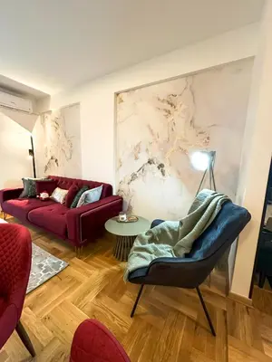 a living room with a red couch and a marble wall at ORDO Apartments in Vrnjačka Banja