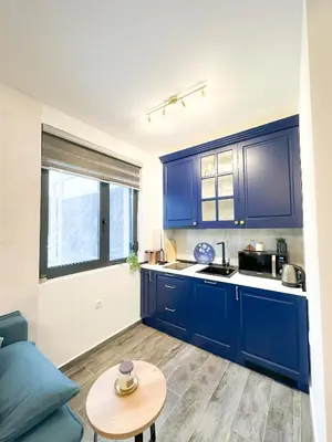 a kitchen with blue cabinets and a table at ORDO Apartments in Vrnjačka Banja