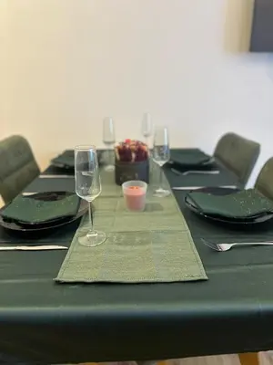 a table with a green table cloth and wine glasses at Apartman B64 Residence Hill Kopaonik in Kopaonik