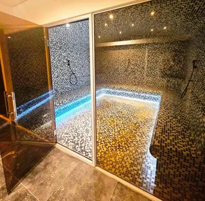a bathroom with a shower with a mosaic wall at Apartman B64 Residence Hill Kopaonik in Kopaonik