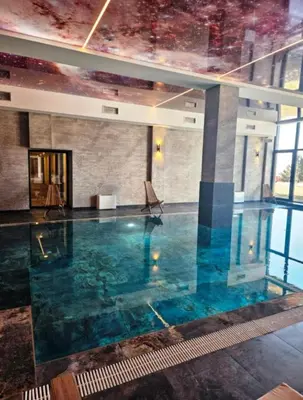 a swimming pool in a building with blue water at Apartman B64 Residence Hill Kopaonik in Kopaonik