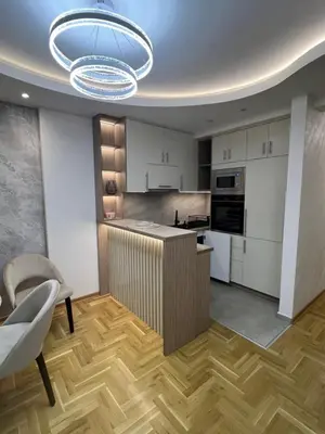 a kitchen with white cabinets and a wooden floor at Apartman Lux Jocić in Vrnjačka Banja