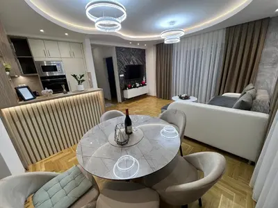 a dining room and living room with a table and chairs at Apartman Lux Jocić in Vrnjačka Banja