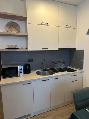 a kitchen with white cabinets and a sink and a microwave at Apartman B64 Residence Hill Kopaonik in Kopaonik