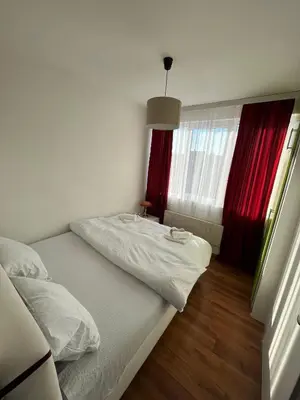 a bedroom with a bed and a window with red curtains at Apartman Stojanovic in Vranje