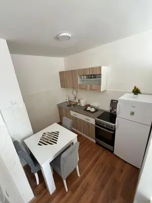 a small kitchen with a table and a white refrigerator at Apartman Stojanovic in Vranje
