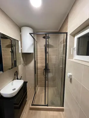 a bathroom with a glass shower and a sink at Apartman 911 in Soko Banja