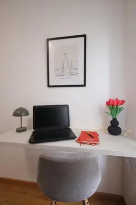 a desk with a laptop and a vase of flowers at Apartman SNEG in Vrnjačka Banja