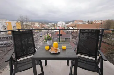 a table with a plate of food on a balcony at Apartman SNEG in Vrnjačka Banja