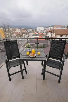 a table with two chairs and two oranges on a balcony at Apartman SNEG in Vrnjačka Banja