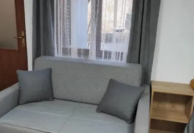 a couch with two pillows sitting in front of a window at Studio Maljković in Knjazevac.