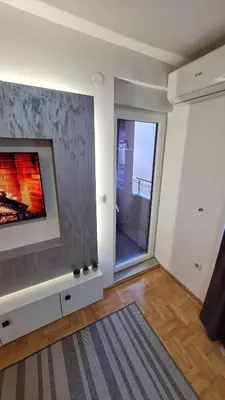 a living room with a fireplace and a window at Apartman Filip in Kruševac