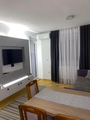 a room with a bed and a table with a television at Apartman Filip in Kruševac