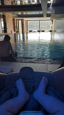 a person laying on a couch in a swimming pool at Apartman Milovan in Kopaonik