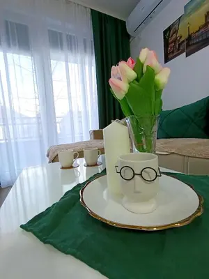 a table with a vase of flowers and glasses on it at MSapartman in Vrnjačka Banja