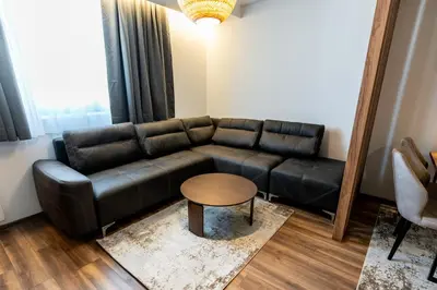 a living room with a black leather couch and a table at Apart-Hotel Ariš Kopaonik in Kopaonik