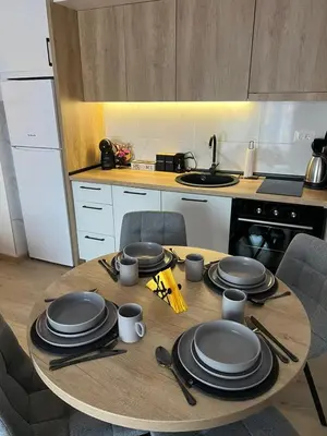 a wooden table with plates and utensils on it in a kitchen at Apartman S in Vrnjci