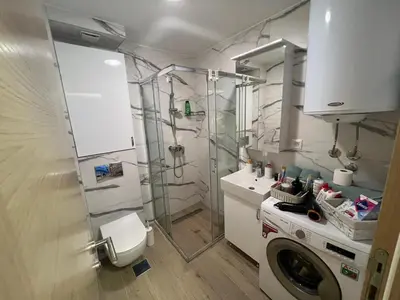 a bathroom with a shower and a washing machine at Apartman S in Vrnjci