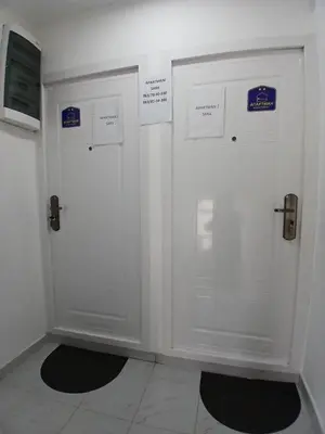 two white doors in a room with signs on them at Apartmani SARA Vranje in Vranje